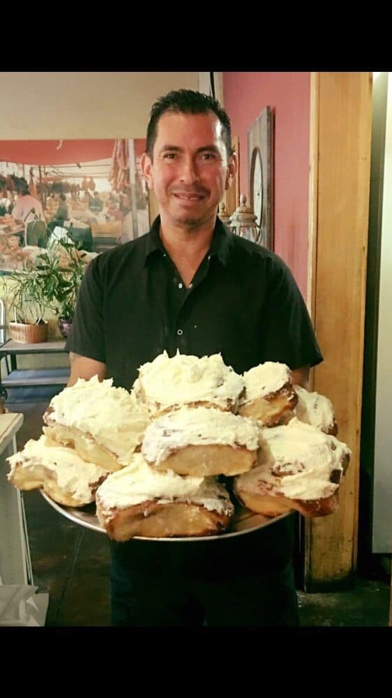 A person happily presenting a pile of their breads