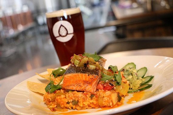 A salmon paella dish with Immersion Beer at the background