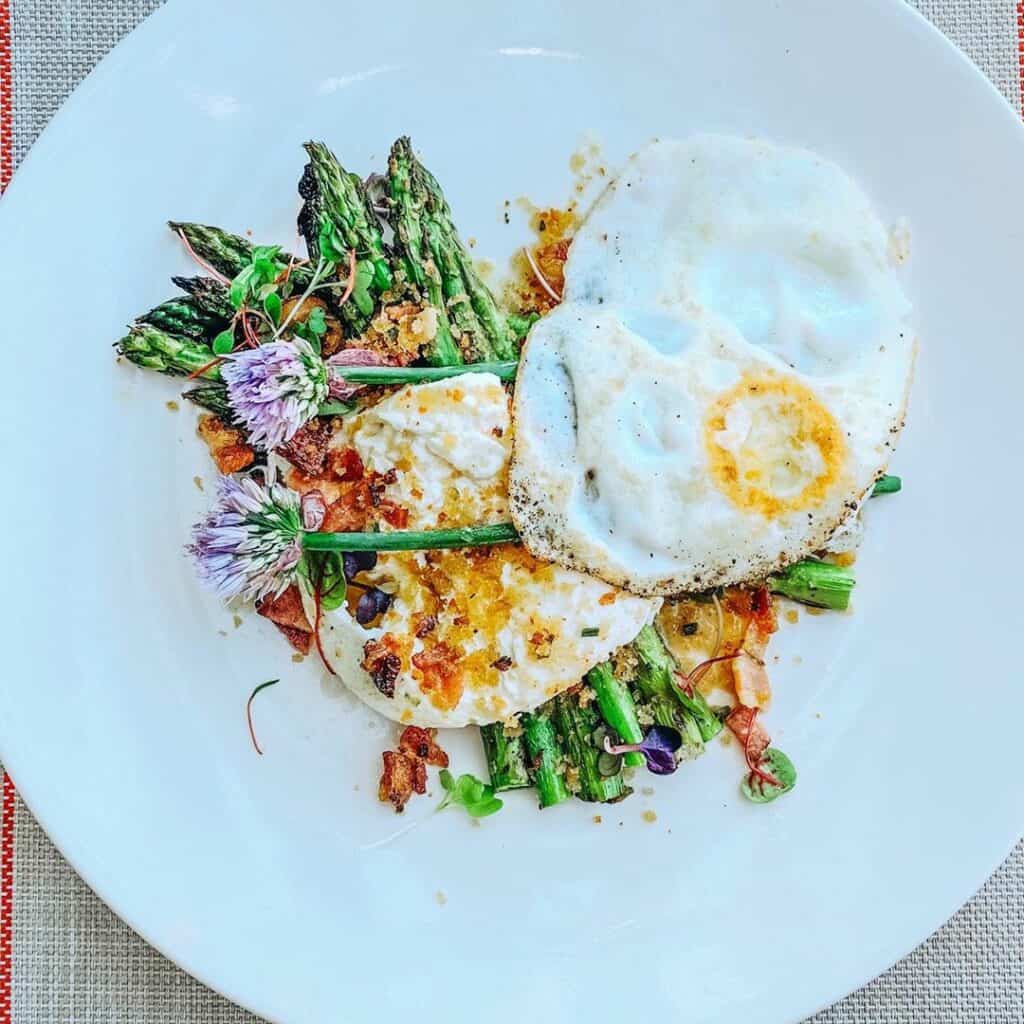 eatdrinkbend-Instagram-2465-ig-17981702260255107 spears of grilled asparagus topped with burrata and bacon vinaigrette and on white plate