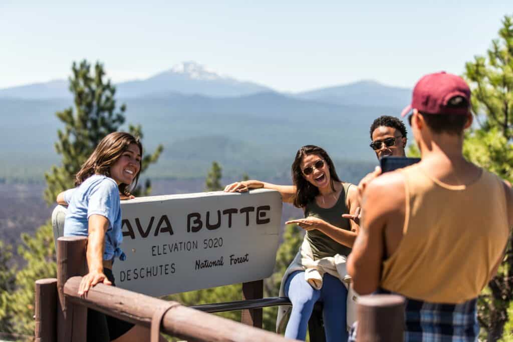 Group of 20-somethings standing around Lava Butte sign near Sunriver, Oregon