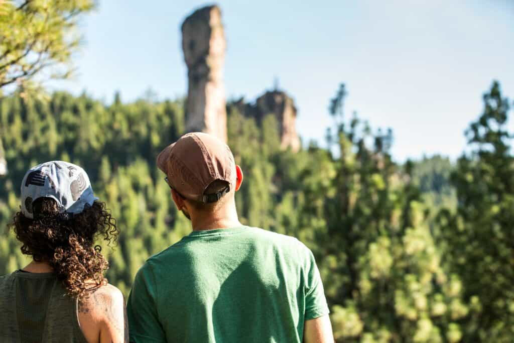 A couple in their 30s looks up at Steins Pillar near Prineville, Oregon