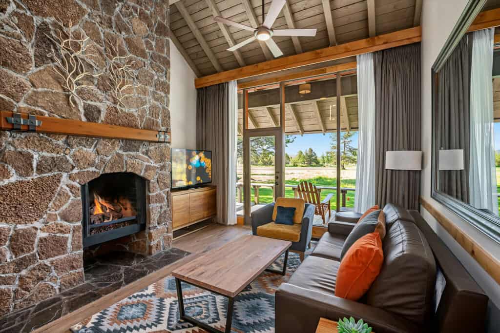 Sunriver-room-146-2-Queens-Suite-(4) the living space with volcanic rock fireplace and patio of the 2-Queen suite Lodge Village at Sunriver Resort