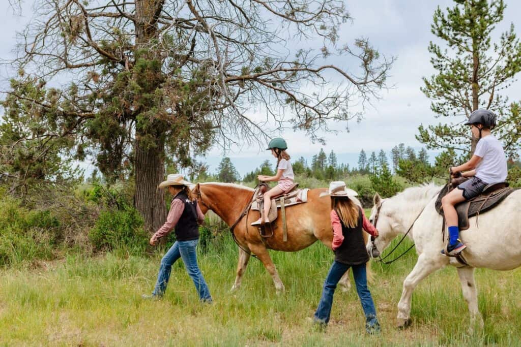 2021-06-22-VCO-Sunriver-19-large two young kids riding the horses as the the trail guides lead the horses through the grass