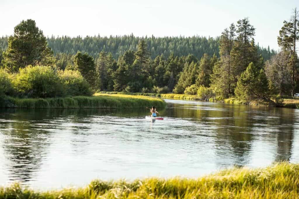 sunriver A woman kneels on a standup paddle board on the Deschutes River in Sunriver, Oregon.