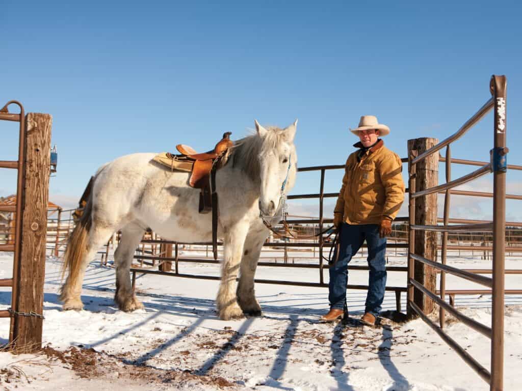 Stables-medium a cowboy standing with his horse at Sunriver Stables