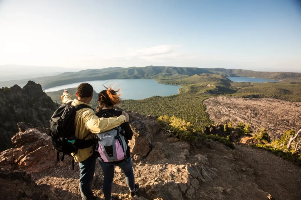 outdoor-adventure travel photography by steve heinrichs_-44-medium Two people stand on a trail overlooking a lake, forest, and obsidian flow.