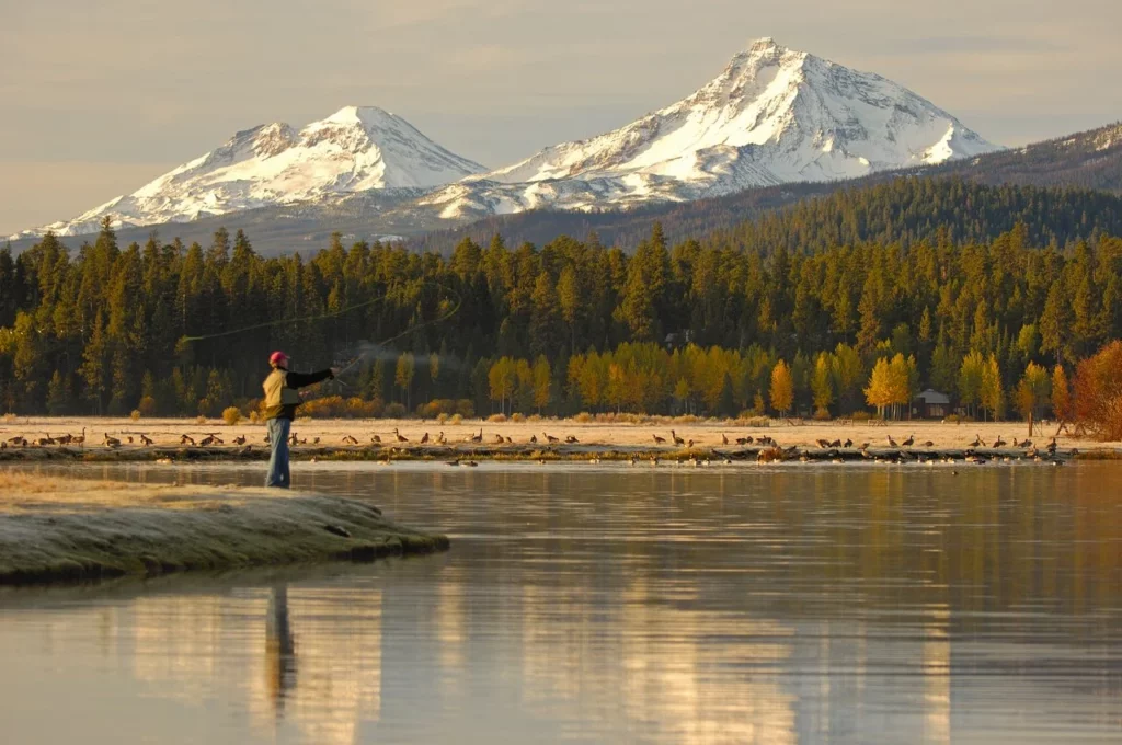 BlackButteRanch-_black-butte-ranch_Fly-Fishing-MikeHouska_DSC2181-medium two people paddle boarding on Phalarope lake under blue skies with the Three Sisters Mountains and a sea of green trees around them